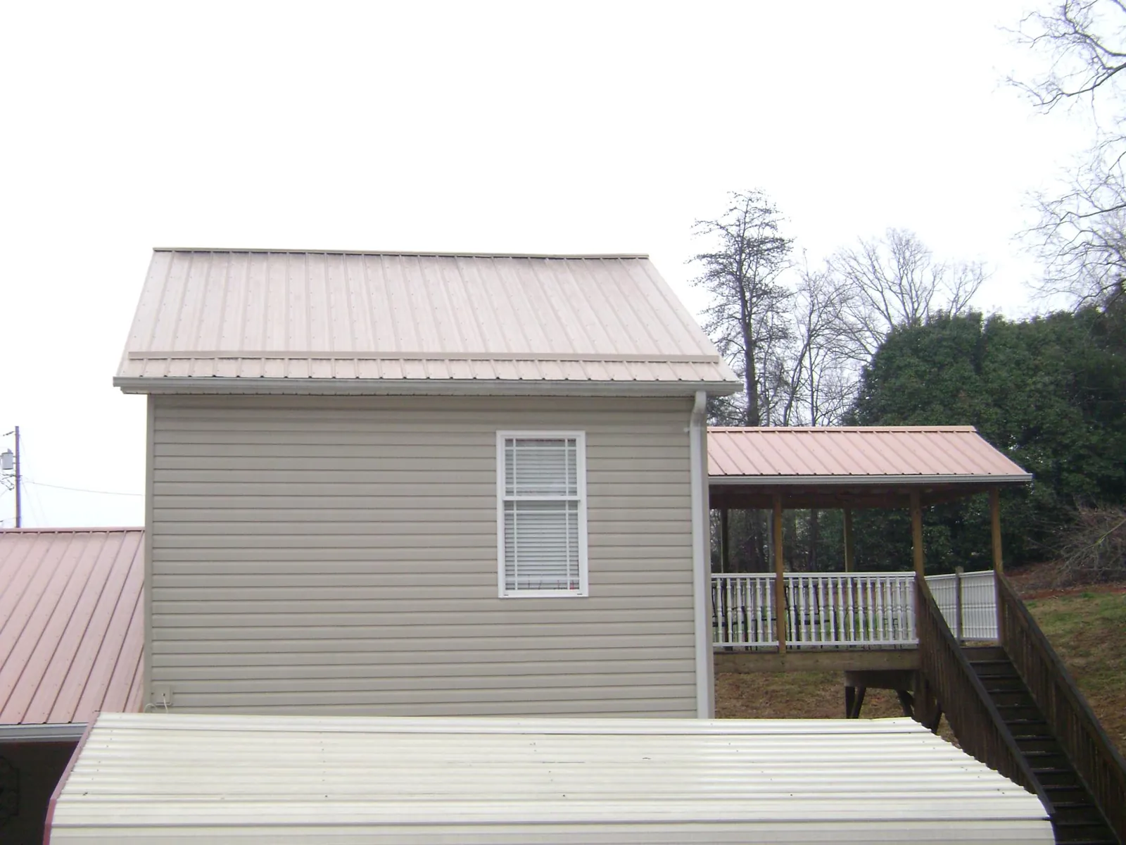 Tan metal roofs on a two story addition and attached porch, from a Roof Replacement job in Roseville