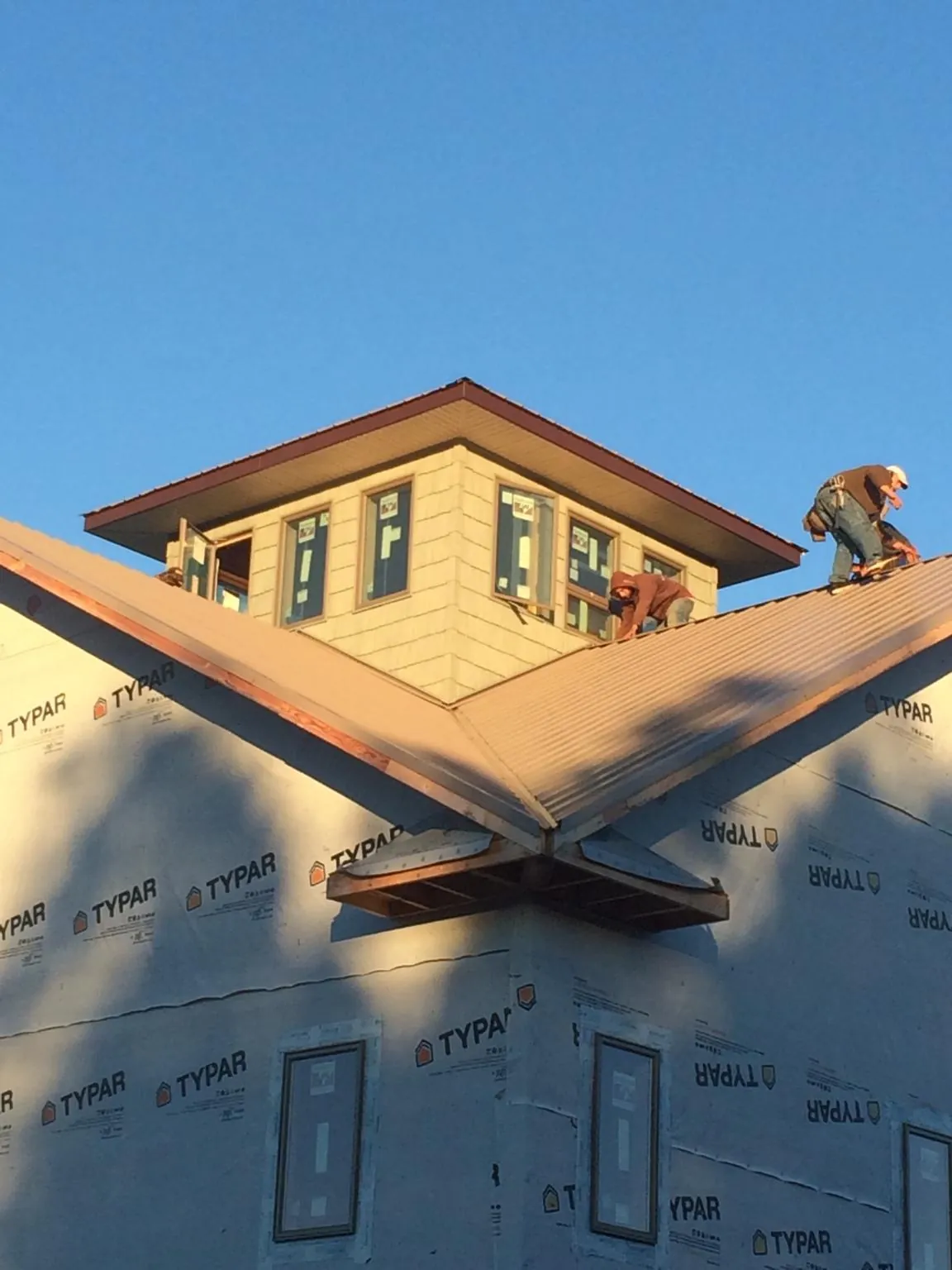 Roofers working around a rooftop cupola on a new metal roof at sunset — Roof Waterproofing in Roseville by Roofing Brothers